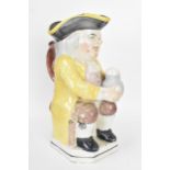 An early 19th century Toby jug, typically modeled seated resting a foaming mug of ale on one knee