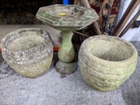 A group of weathered garden concrete planters with one column stands, along with a pedestal bird