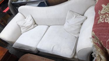 A large two seater sofa, upholstered in cream on block feet, with loose cushions Location: