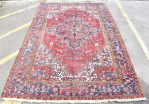 A Persian Heriz hand woven rug, having a red ground with a central motif within a field of