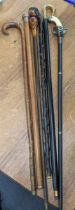 A mixed group of walking sticks to include a silver handled stick, one stick with a handle fashioned