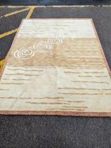 A contemporary cream and beige rug with swirl and line decoration 242cm x 175cm Location:
