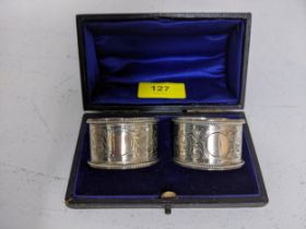 A cased pair of Edward VII silver napkin rings decorated with floral engraving between a beaded