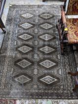 A Middle Eastern handwoven green ground rug having two vertical rows of seven elephant gulls,