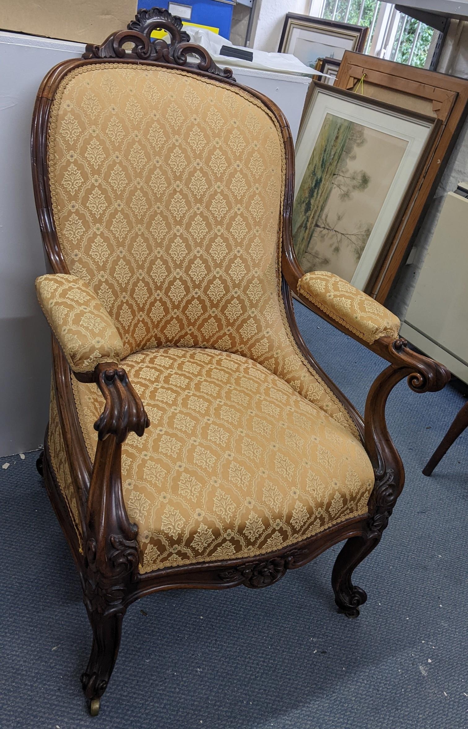 A Victorian rosewood salon armchair having scrolled arms with a serpentine front, cabriole front