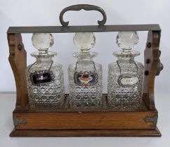 An early 20th century oak Tantalus with three decanters, no key Location: 1.5