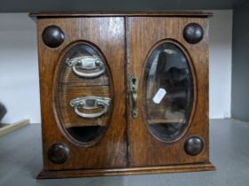 An early 20th century smokers/table top cabinet, twin glazed doors, internal drawers and open