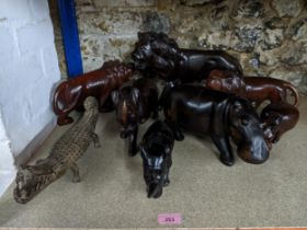 A group of African carved wooden animal models, rhino, hippos and lions, along with an African