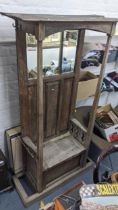 An early 20th century oak hall stand with coat hooks, bevelled mirror and a hinged seat 188hx107w