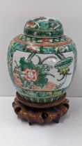 A late 19th/early 20th century Chinese Famille verte ginger jar, raised on a treen carved stand A/