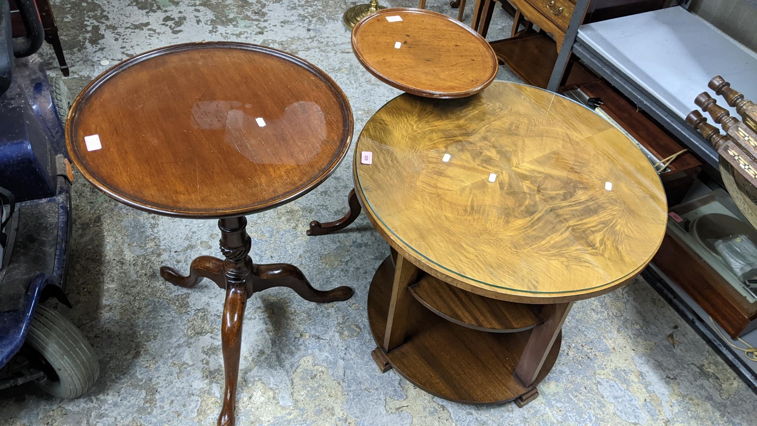 An Art Deco period walnut three tier circular table with quarter cut and glass top, supported on