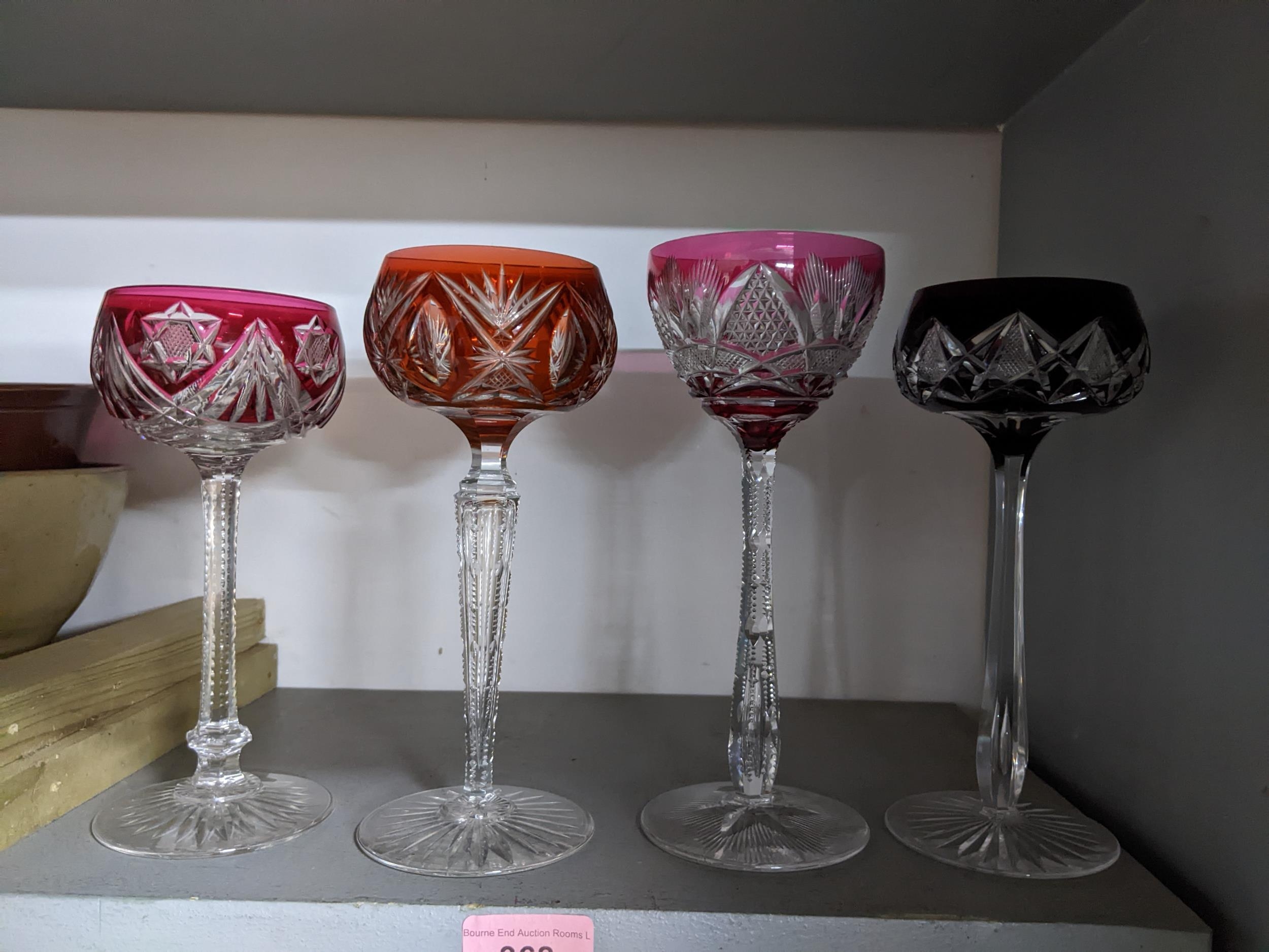 A group of four cut glass and overlaid hock glasses, each with different coloured bowls and patterns