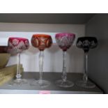 A group of four cut glass and overlaid hock glasses, each with different coloured bowls and patterns