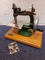 A 1940's Grain child's manual sewing machine together with a silver tone model of a sewing