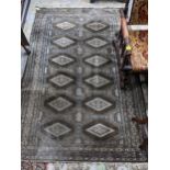 A Middle Eastern handwoven green ground rug having two vertical rows of seven elephant gulls,