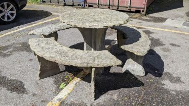 A modern carved slate circular garden table and three benches to