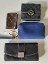 Four designer wallets comprising a small Gucci black canvas wallet, a Lulu Guiness blue wallet, a