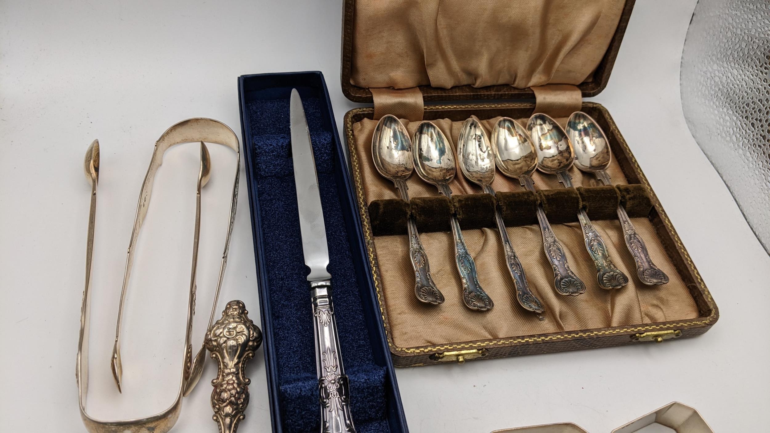 A group of mixed silver items to include three pairs of silver sugar tongs, a case set of silver tea - Image 2 of 3