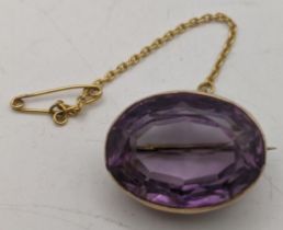 A yellow metal brooch tested as 9ct set with an amethyst coloured stone and a fine chain 6.6g