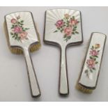 A set of three early 20th century enamelled silver dressing table set decorated with flowers