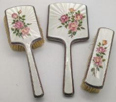 A set of three early 20th century enamelled silver dressing table set decorated with flowers