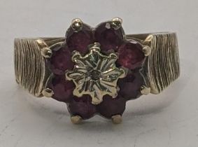 A 9ct gold ruby flower head cluster ring set with a central diamond, with ribbed sides, size N, 4.1g