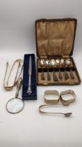 A group of mixed silver items to include three pairs of silver sugar tongs, a case set of silver tea