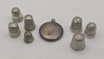 A group of white metal and silver thimbles to include one having a floral engraved pattern, along