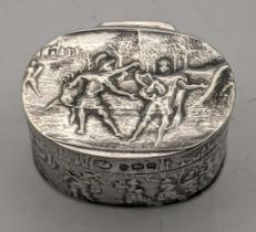 A late 19th/early 20th century silver pill box with embossed decoration with a countryside landscape