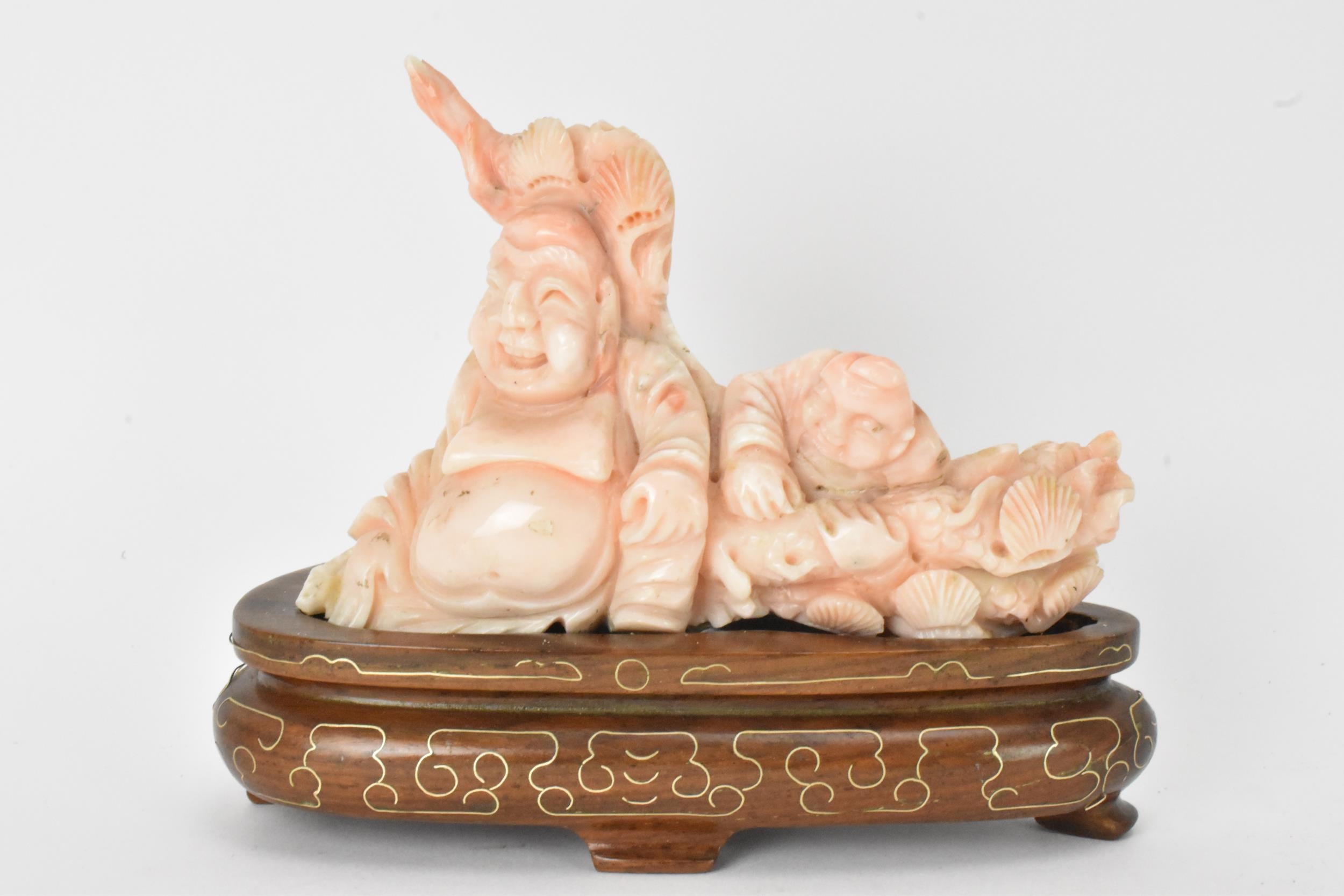 A Chinese 20th century coral carving depicting a laughing Buddha with child among a nautical