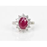 An 18ct white gold, diamond and ruby dress ring, set with central oval mixed cut ruby in four claw