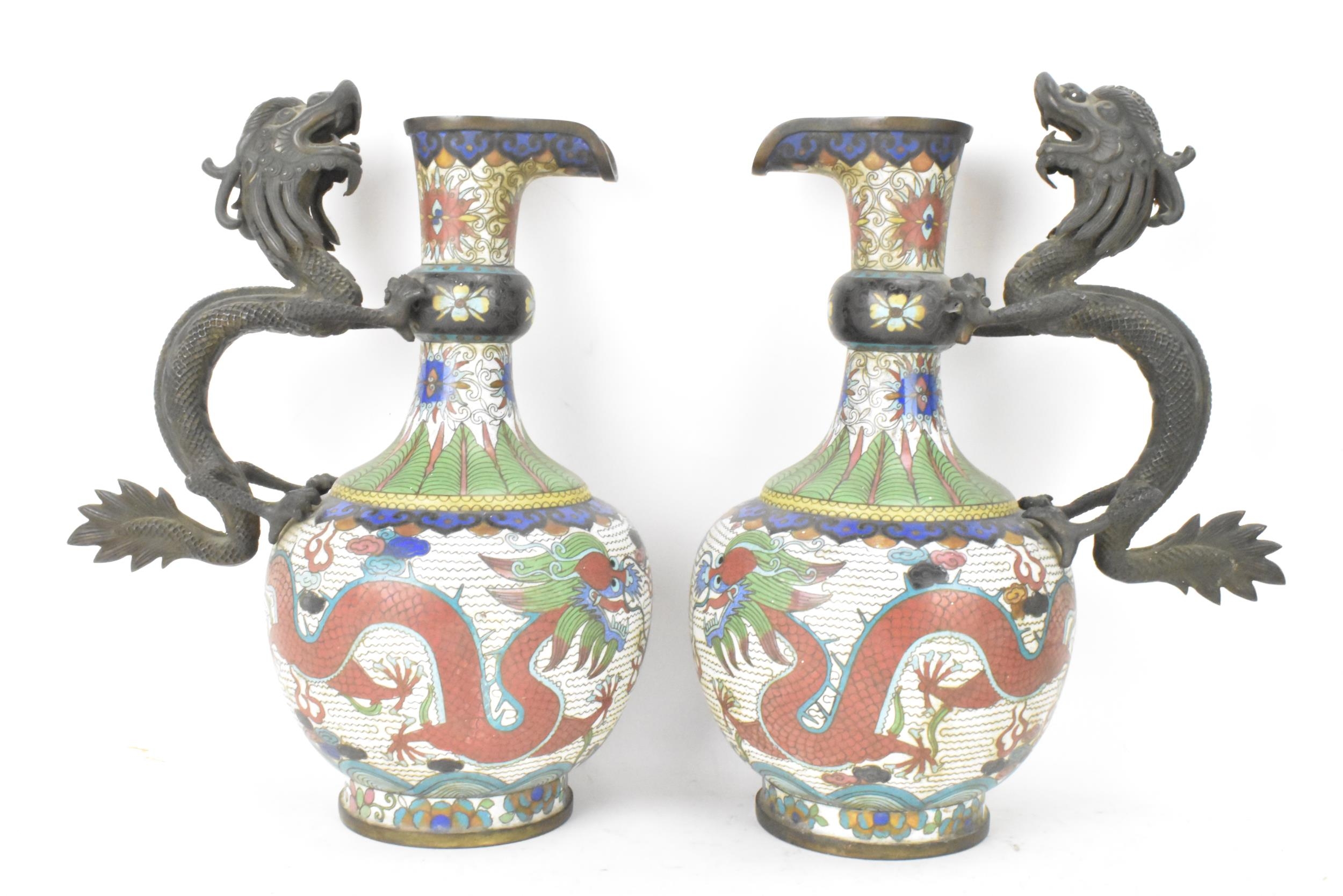 A pair of Chinese late Qing dynasty cloisonne ewers, both having a handle modelled in the form of