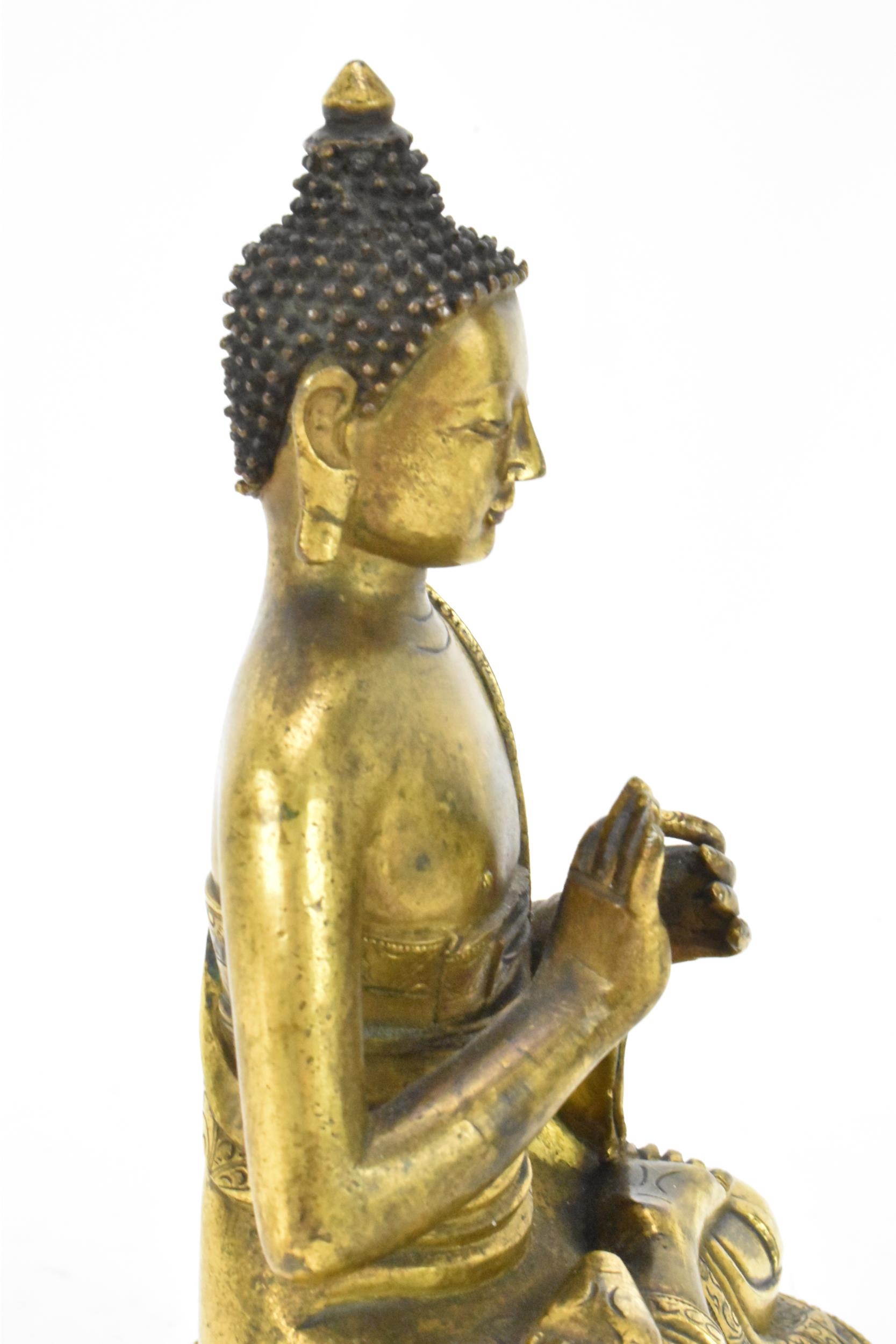 A Sino Tibetian gilt bronze figure of Buddha, 18th/19th century, dressed in monastic robe, with - Image 15 of 16