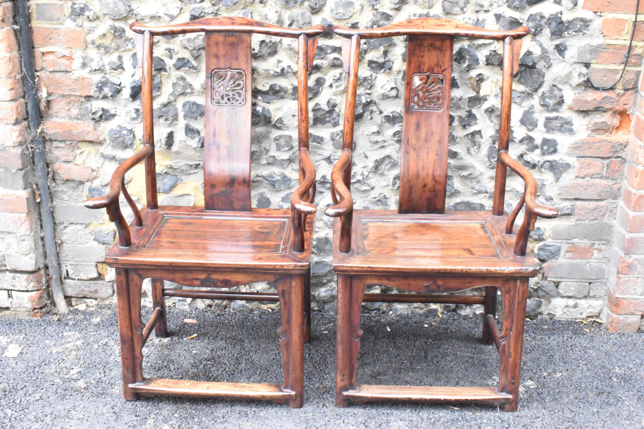 A pair of 20th century Chinese Ming style yoke back hardwood armchairs, with curved top rail and