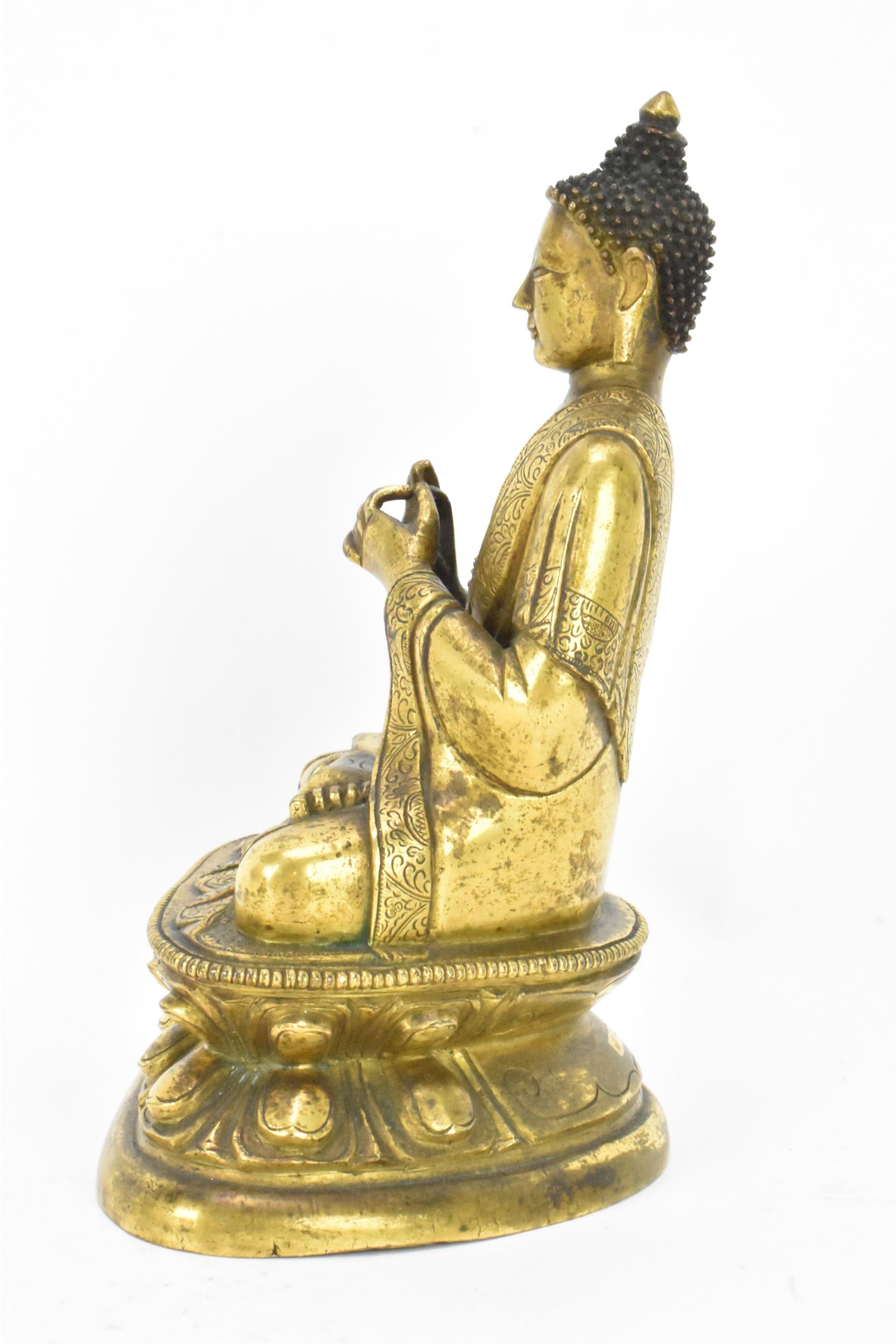 A Sino Tibetian gilt bronze figure of Buddha, 18th/19th century, dressed in monastic robe, with - Image 2 of 16