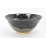 A Chinese Cizhou type bowl, of conical form and covered in a dark lustrous glaze falling short of