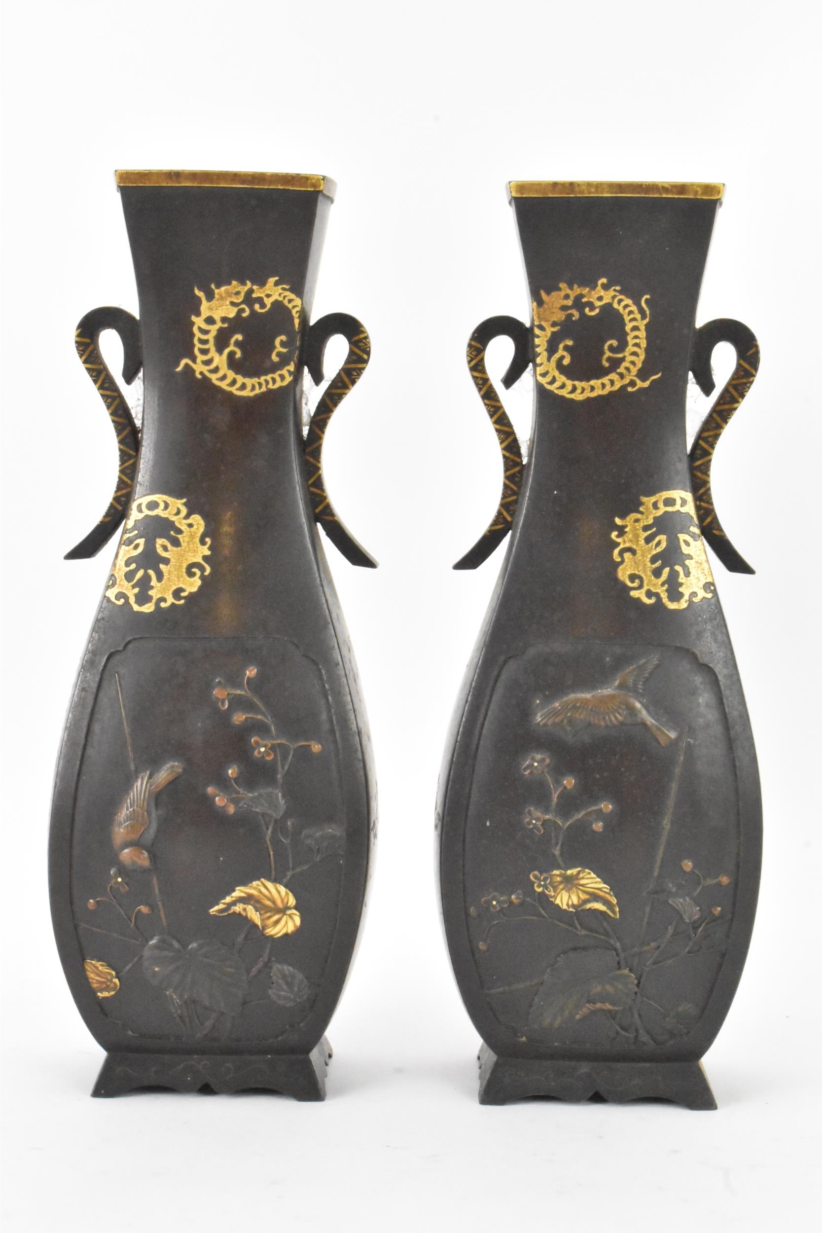A pair of Japanese Meiji period iron vases, decorated with panels depicting birds and flowers in