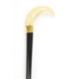 An Edwardian ebonised walking stick, with a warthog tusk handle, brass bound collar and a tapered