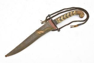 An early 20th century middle eastern dagger, having a horn handle and leather sheath decorated