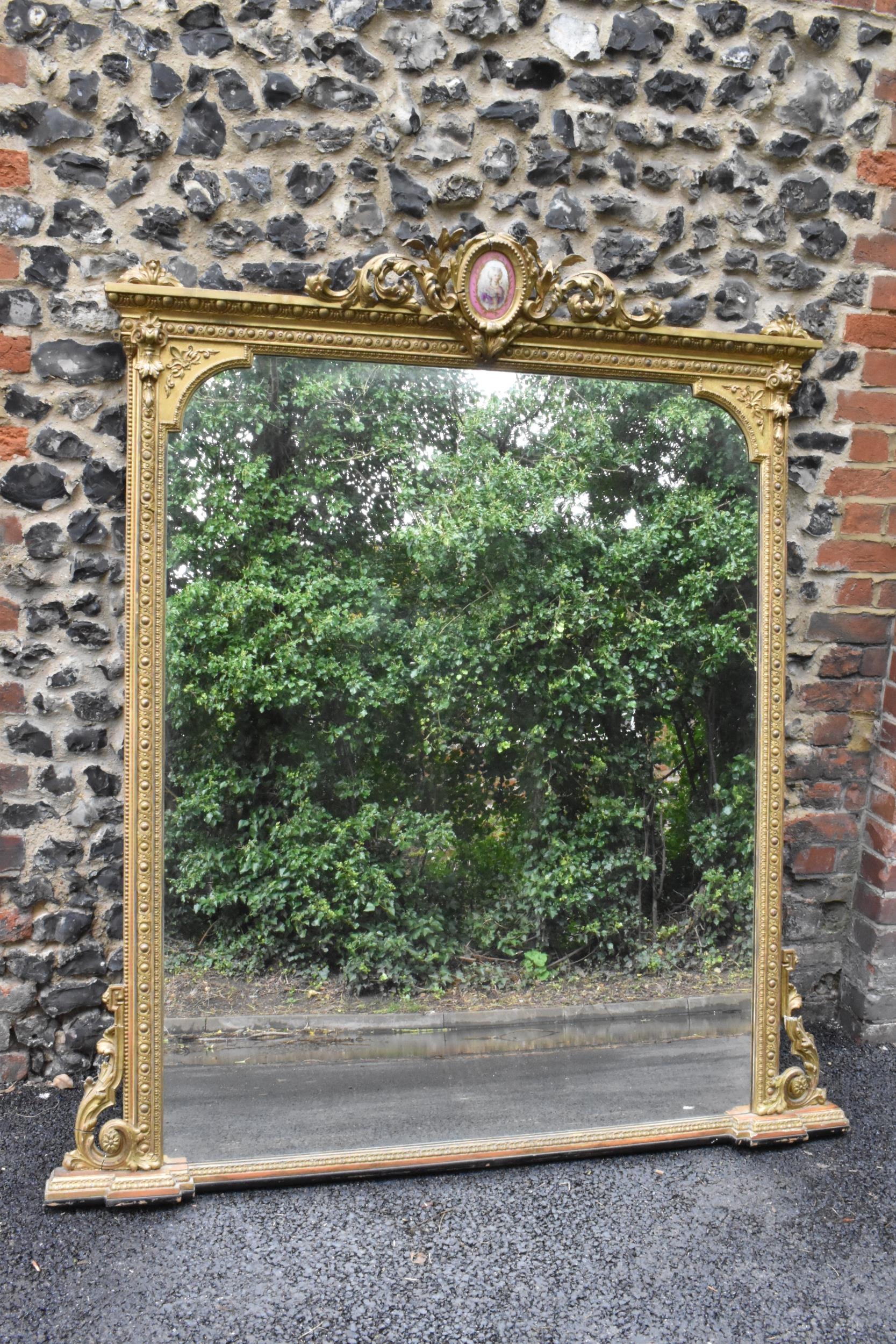 A 19th century French Louis XVI style large gilt wall mirror, having a sevres style painted plaque