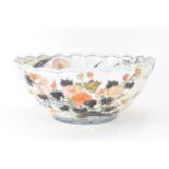 A Japanese Edo period Arita Imari porcelain punch bowl, circa 1700, having a shaped rim and fluted