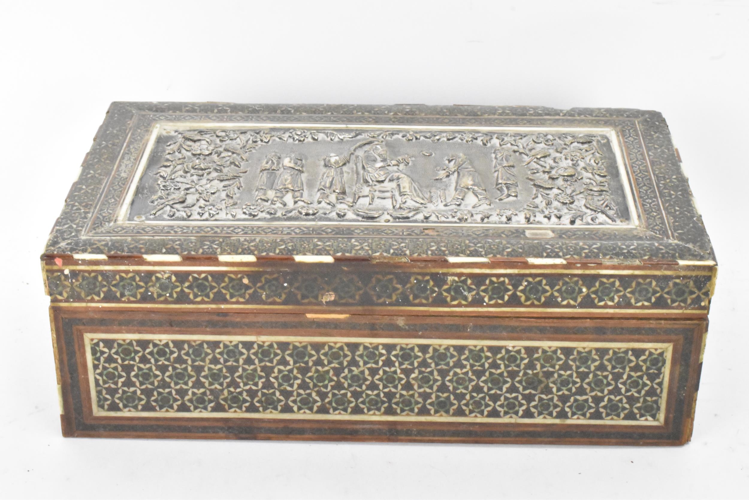 A late 19th century Indo-Persian cigarette box, decorated with a silver repousse panel to the lid