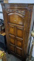An early 20th century oak carved single door wardrobe having a panelled door, a single shelf,