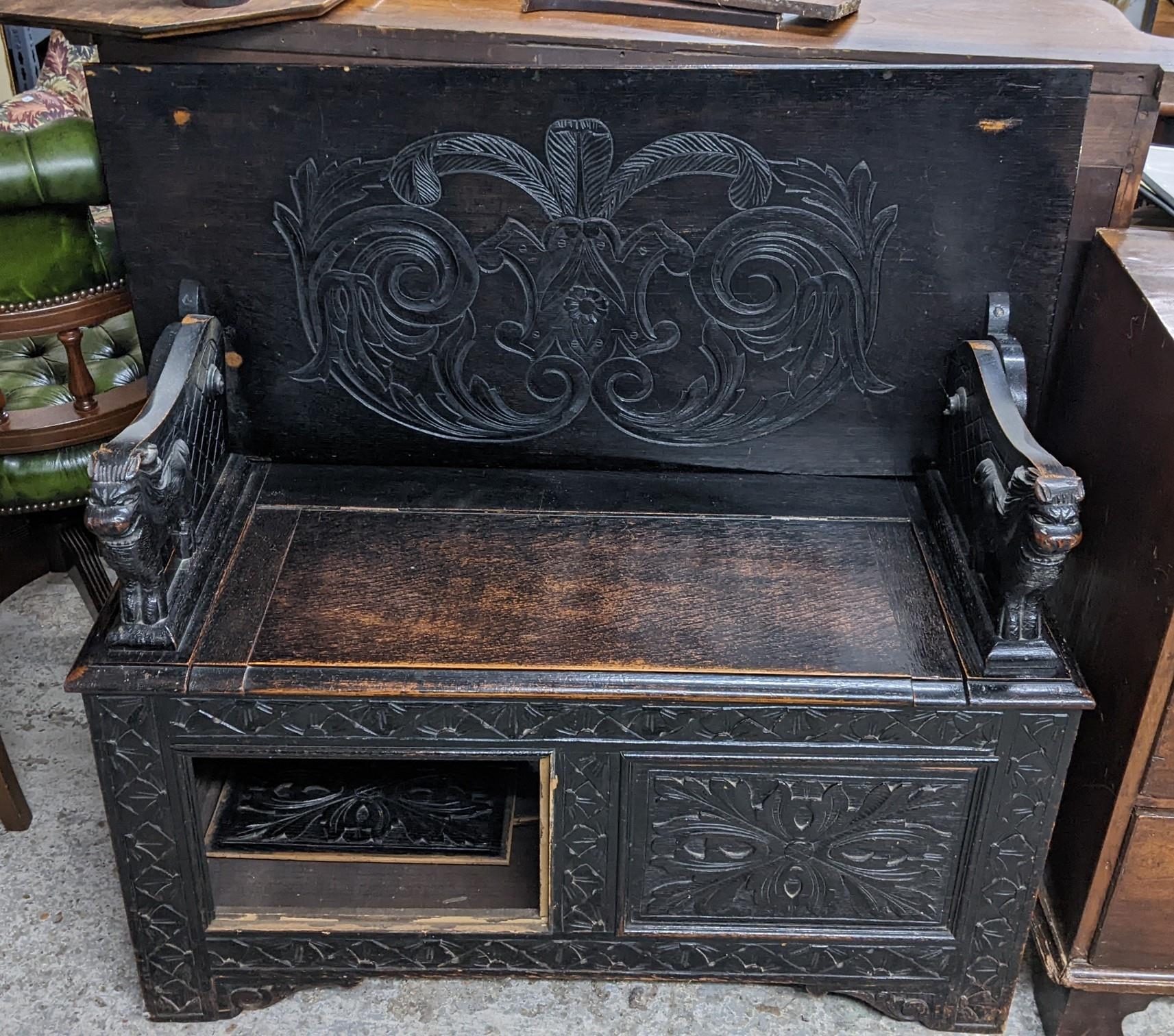 An early 20th century oak monk's bench having carved panels and lion formed arms 75cm h x 106cm w