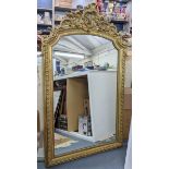 A late 19th/early 20th century French ornate gilt mirror, decorated with C scrolls, beaded and