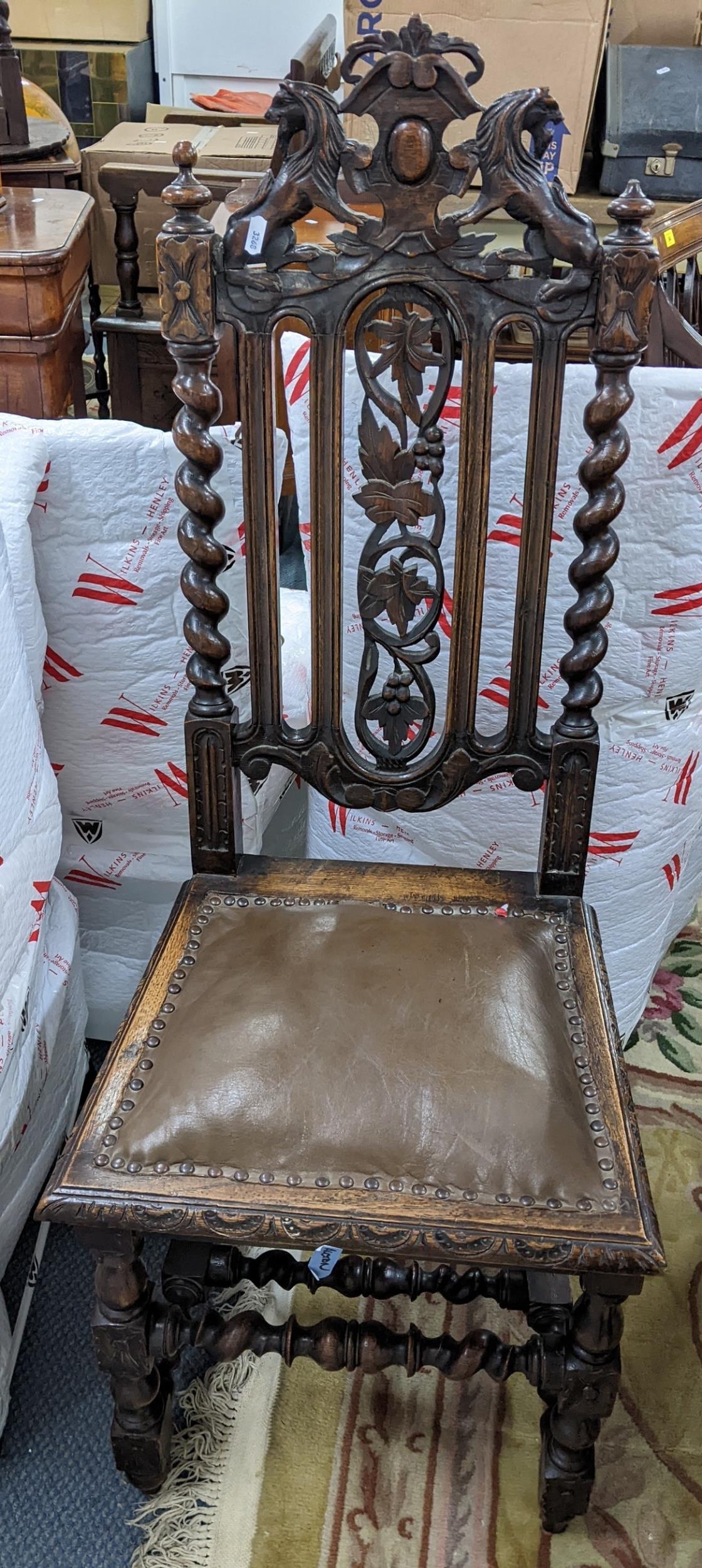 A late Victorian oak carved hall chair, the top surmounted by lions and having barley twist supports