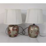 A pair of modern Oriental style table lamps decorated with parrots and floral decoration on a gold