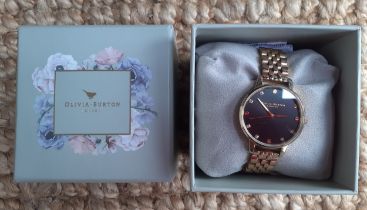 A modern Olivia Burton gold tone ladies watch having a black dial, additional strap links and