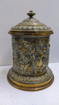 A late Victorian brass embossed tobacco jar, decorated with a continuous scene of figures, 18.5cm