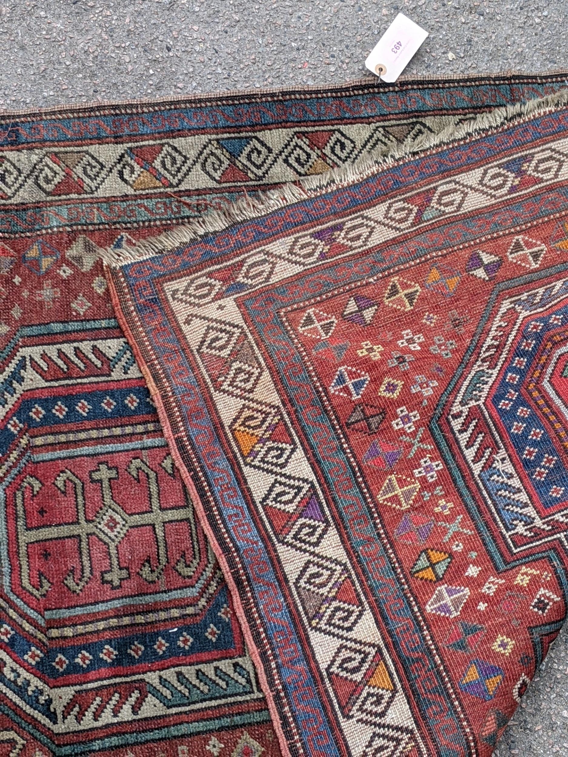 A Kazak rug decorated with symmetrical abstract motifs surrounded by quartered coloured geometric - Image 7 of 7